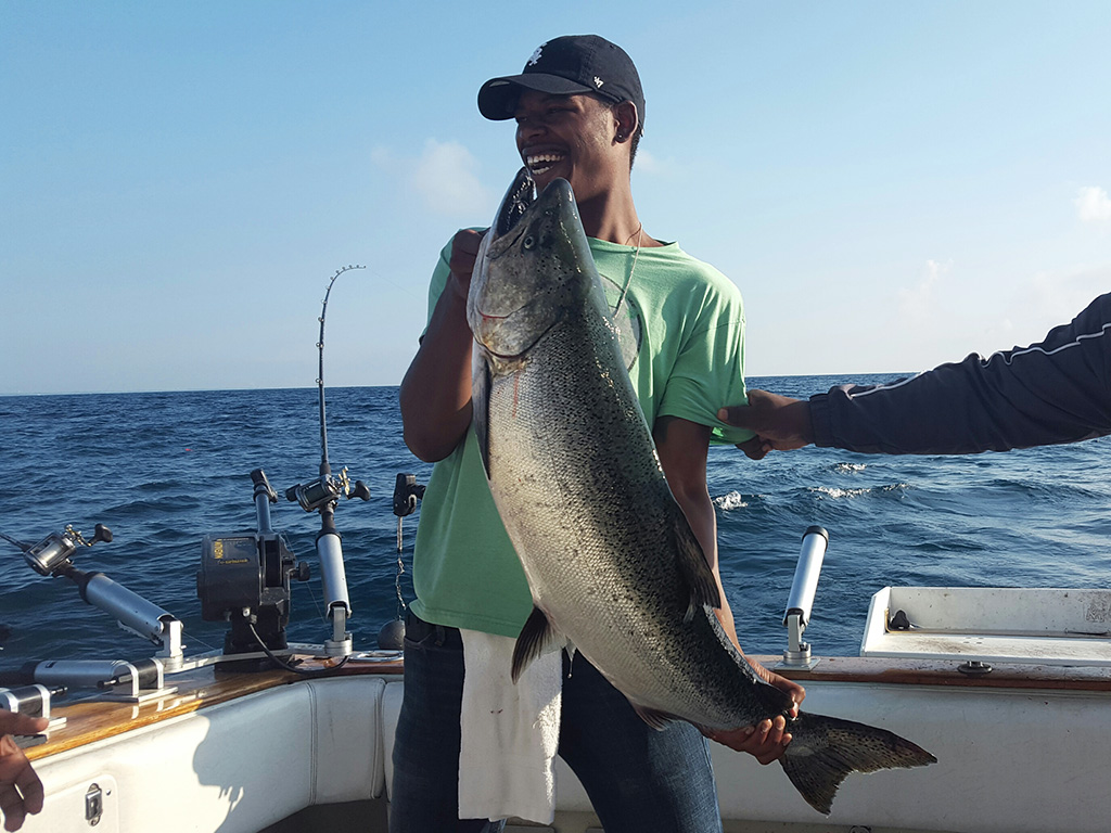 A smiling angler holds up a big King Salmon he recently caught on a trolling trip.