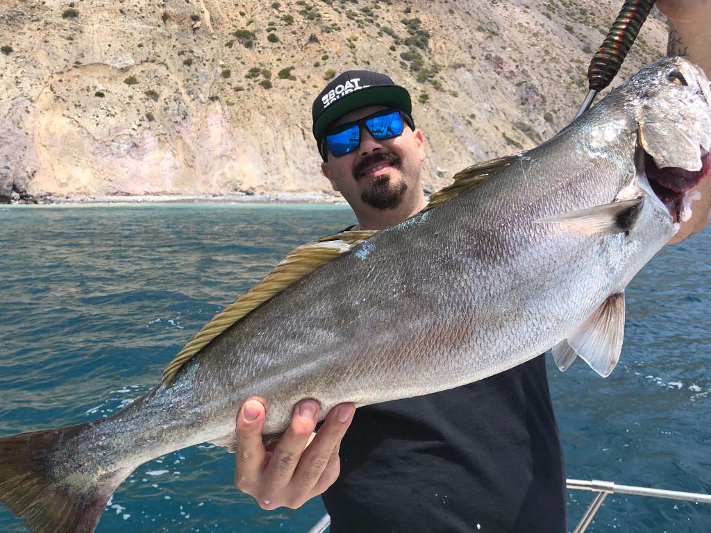 A smiling angler holds up a White Seabass recently caught while fishing in Huntington Beach.