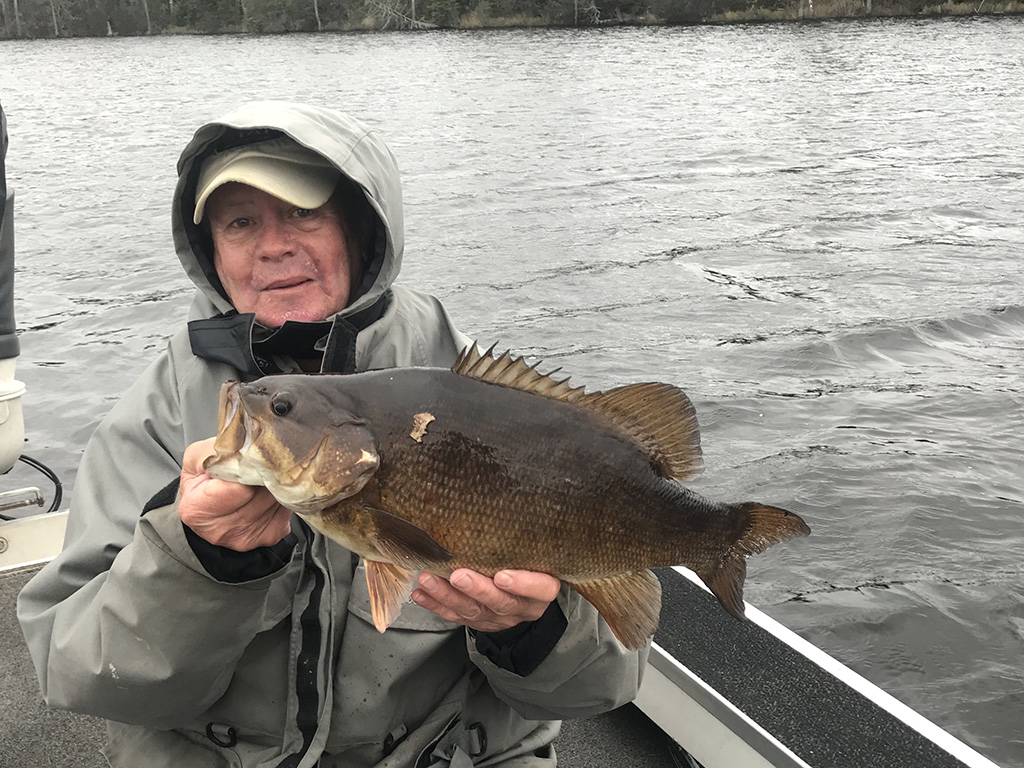 A sitting angler holds up a Smallmouth Bass he caught on Lake Winnebago.