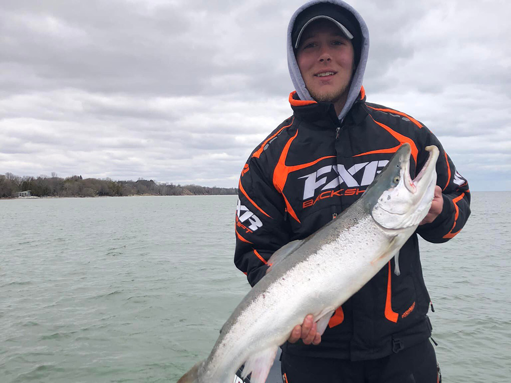 A smiling angler hods up a Steelhead he recently caught close to Lake Michigan.