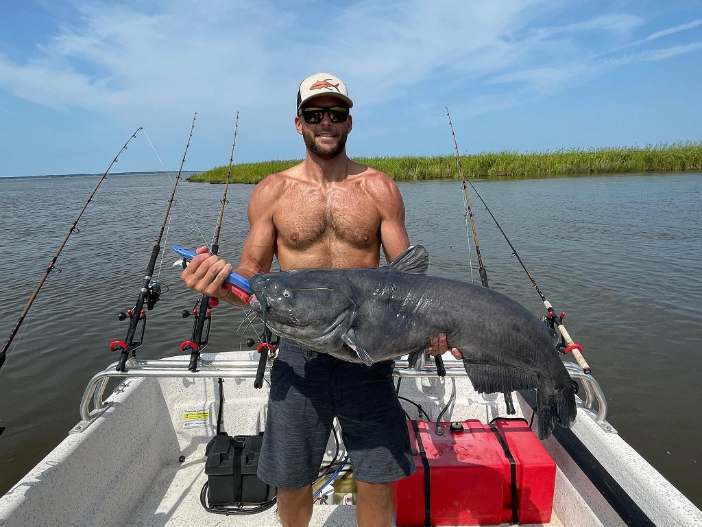 A happy angler on a boat holds a big Catfish he recently caught near Corolla, NC.