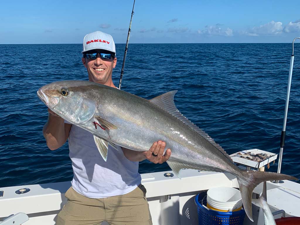 A smiling angler posing for a photo with an Amberjack he caught deep sea fishing off the coast of Marco Island.