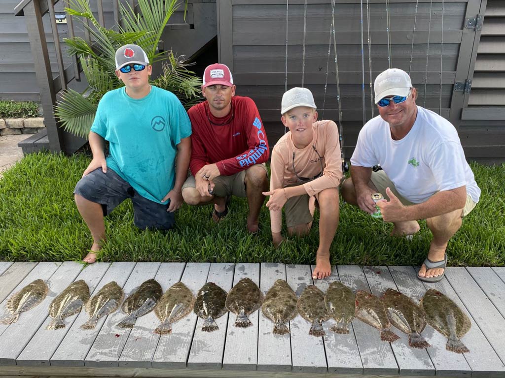 Two adult anglers and their kids posing behind their Flounder catches back at the dock near Trinity Bay