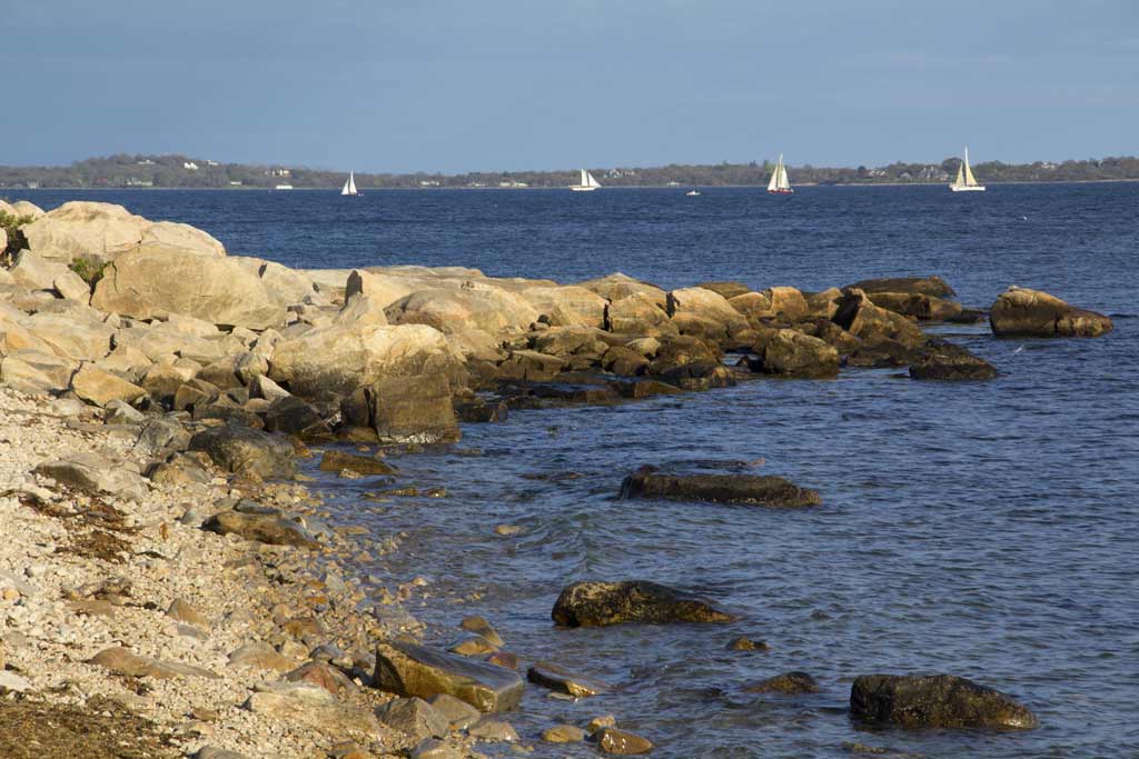 A jetty on the Long Island Sound in Connecticut with sailing boats in the distance