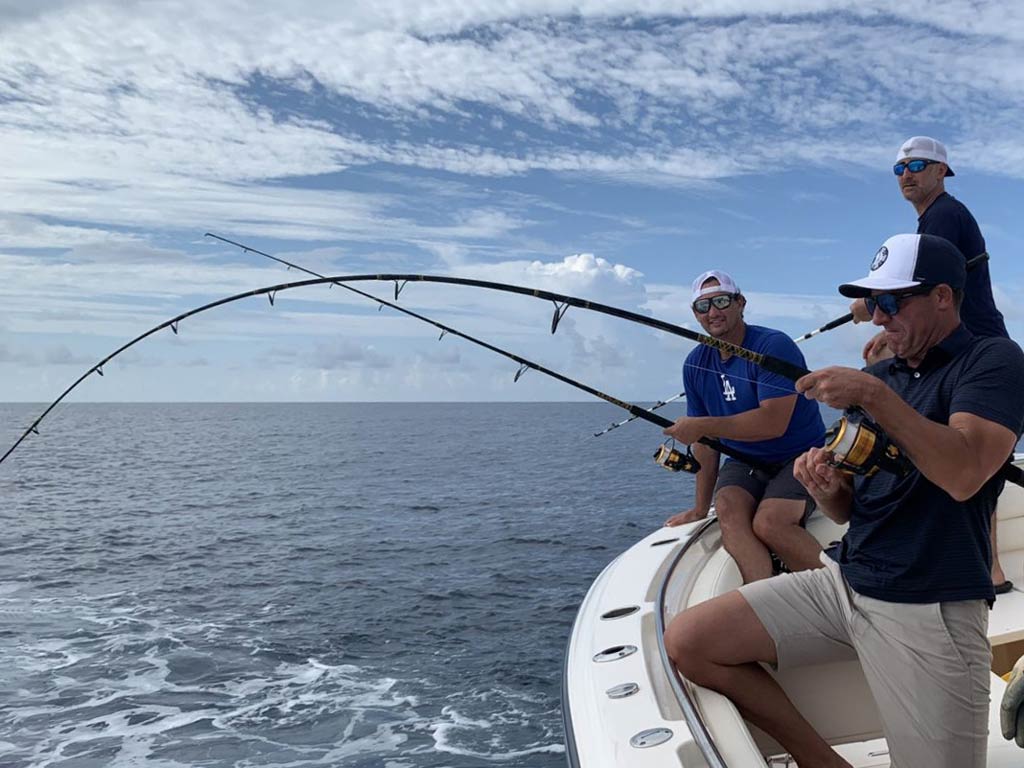 A view from the side of several anglers bottom fishing from a charter boat