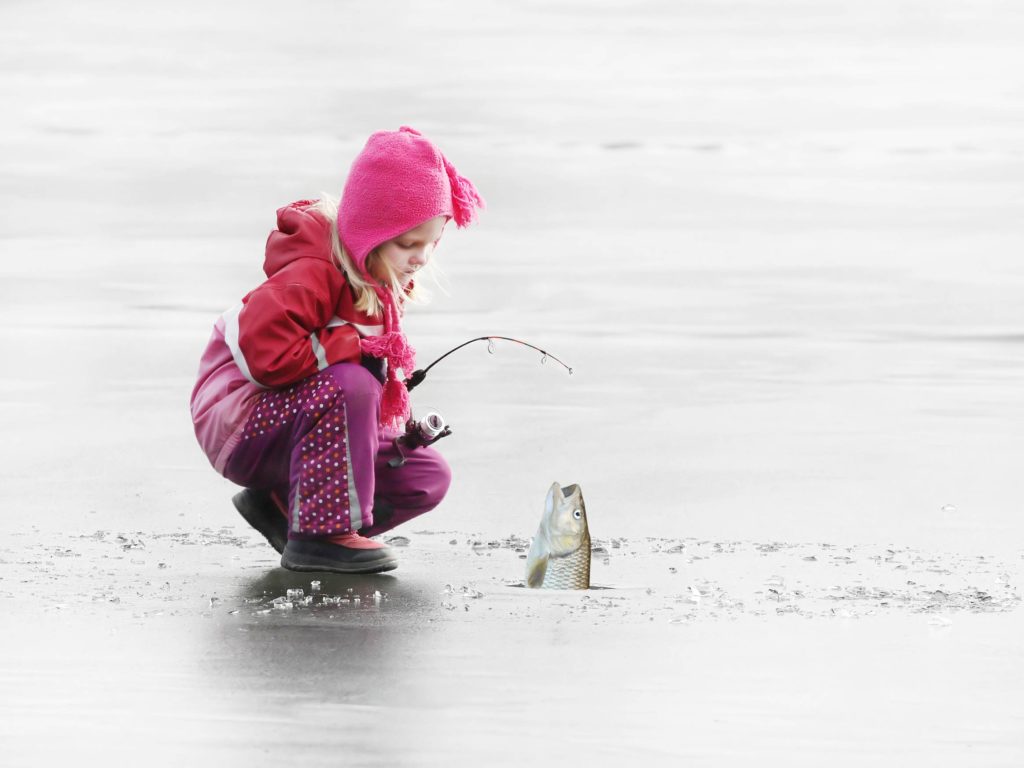 Младо момиче навива риба, която е уловила в замръзнало езеро в Канада.