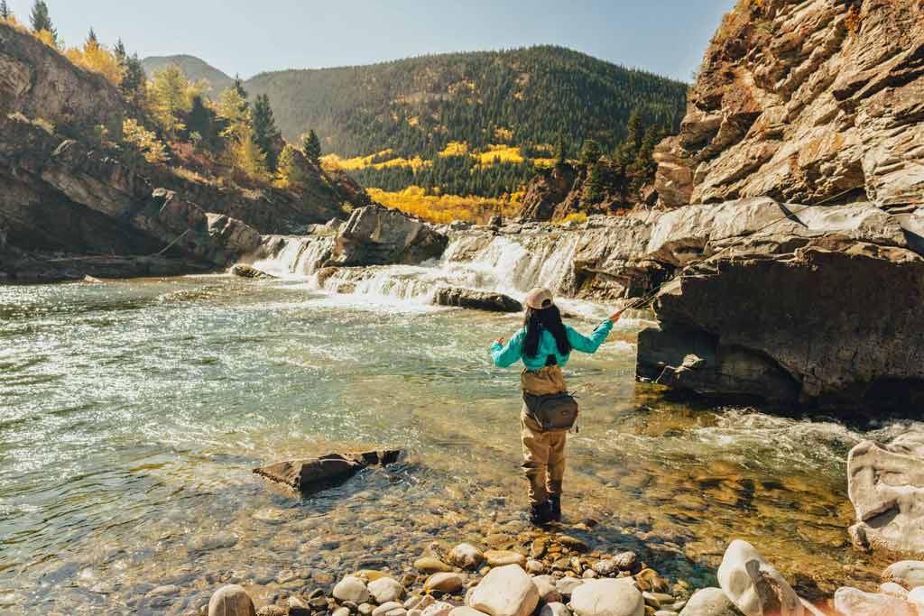 A woman fly fishing on a rocky river near Calgary