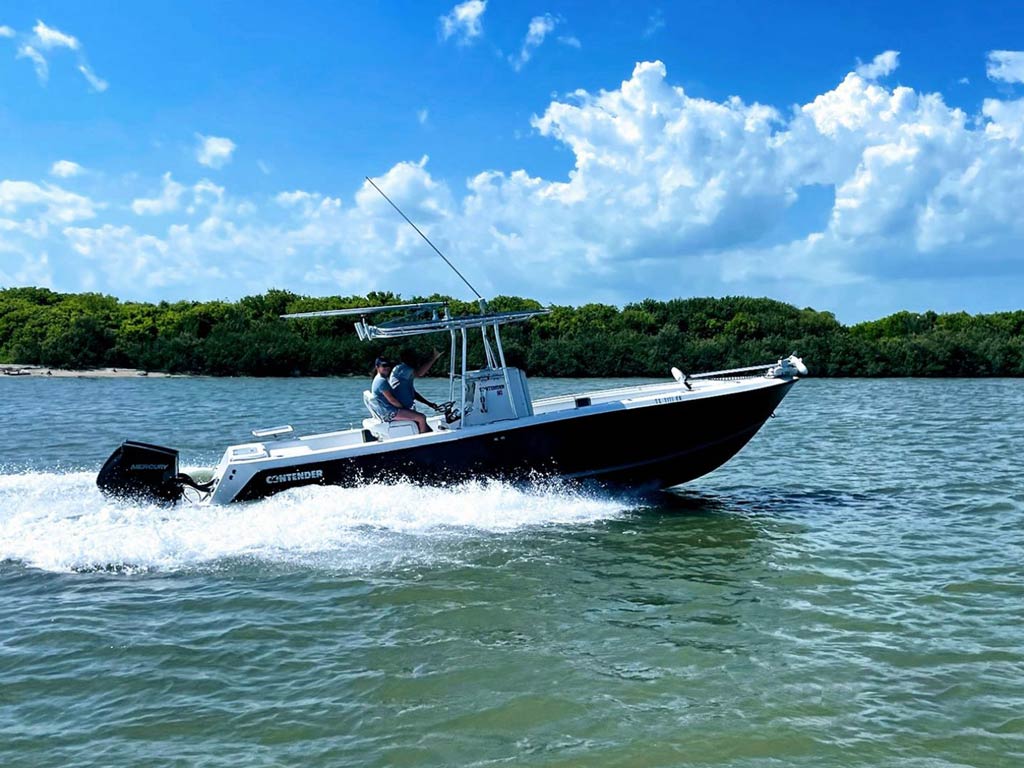 A captain on a typical Trinity Bay fishing charter boat against greenery and white clouds in the background