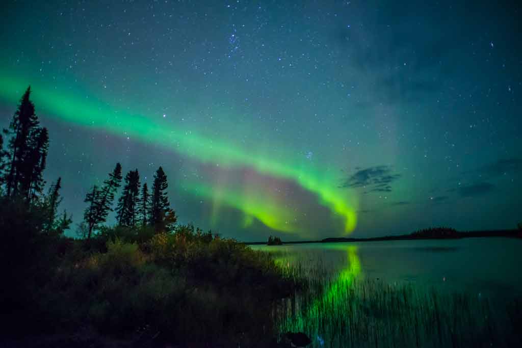 Dauphin Lake at night, with northern lights above the shores