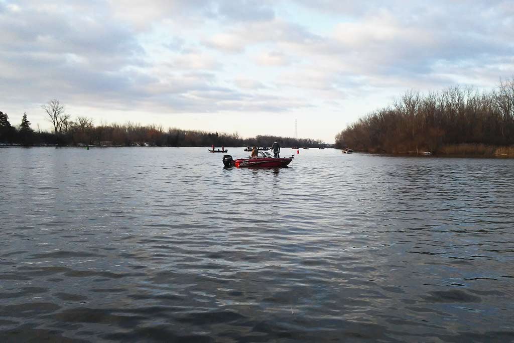 A view from the water of a fishing wend with people fishing on it on the Saginaw River