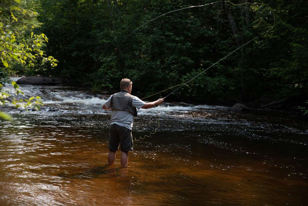 A man standing in a river and tossing a fly with his fly fishing rod