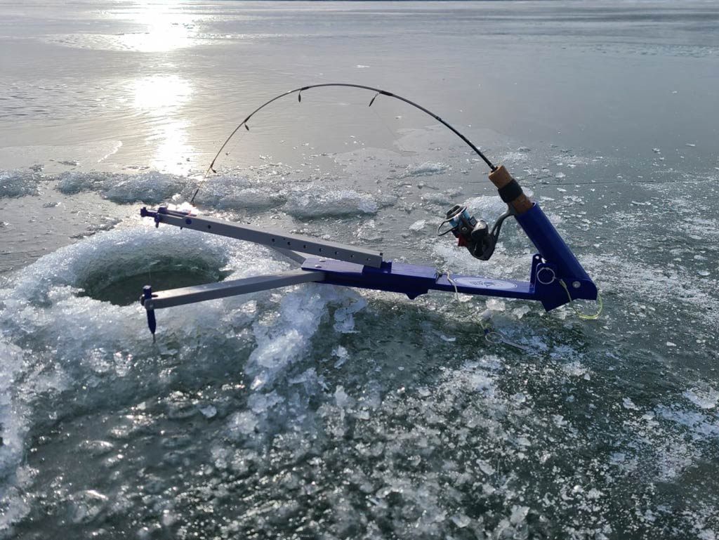 A sunset view of the frozen lake and ice fishing equipment placed above the hole