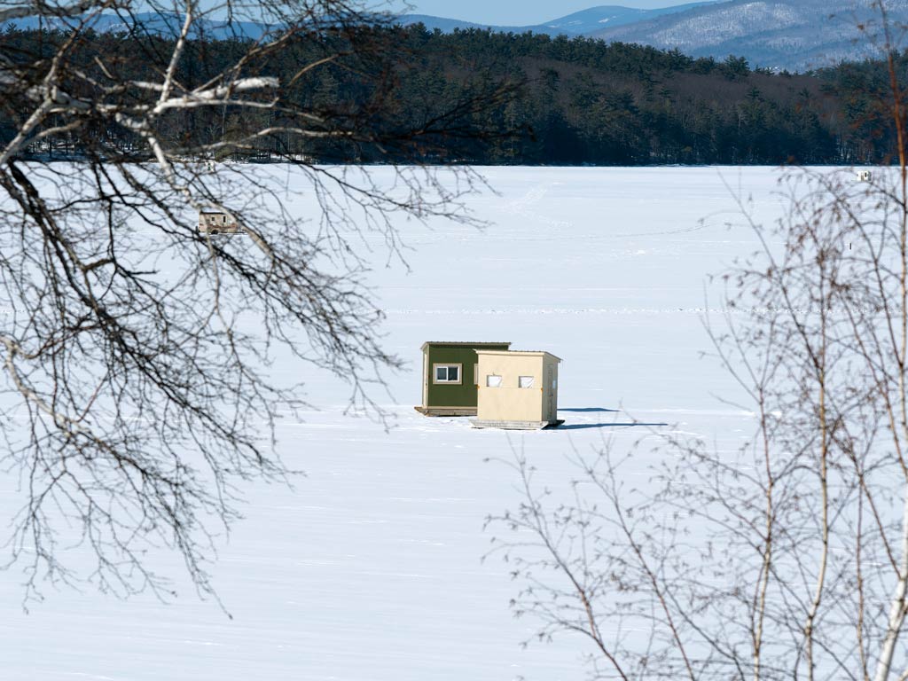 A distant view of two shanties on the frozen Lake Winnipesaukee during the ice fishing season in New Hampshire