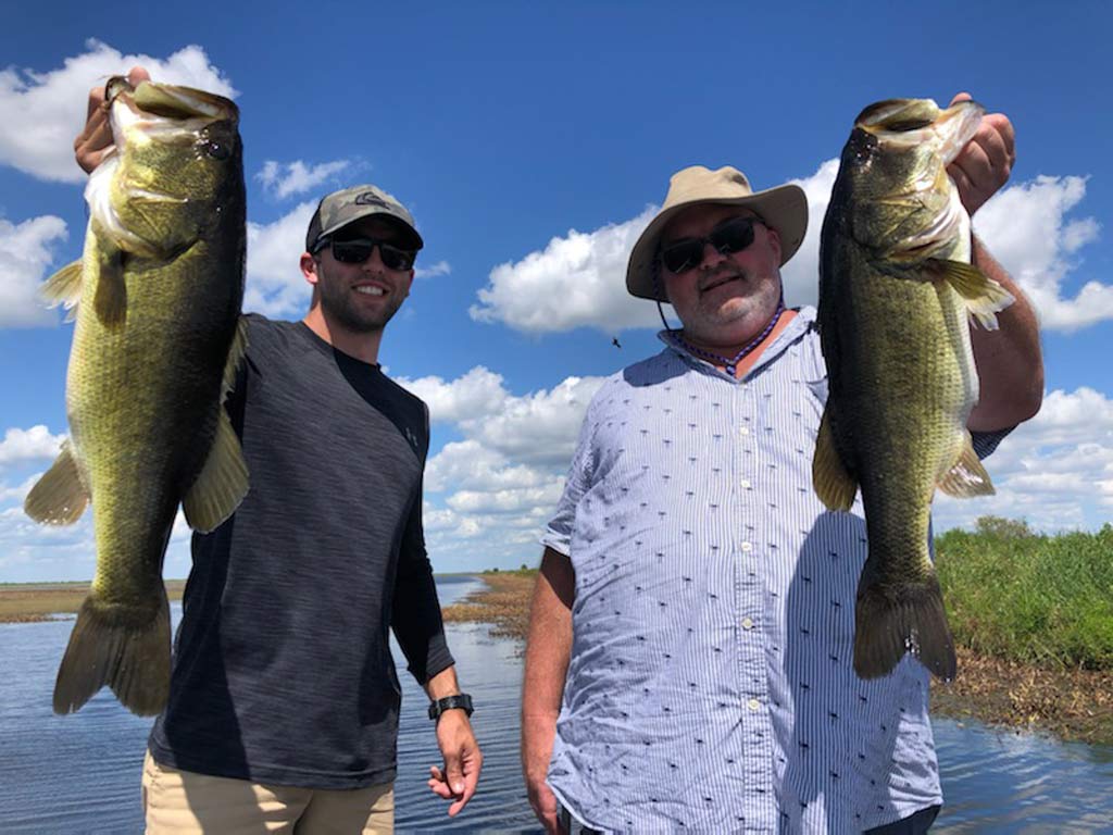 Two anglers posing for a photo, each holding a Largemouth Bass caught in Lake Tohopekaliga, south of Orlando.