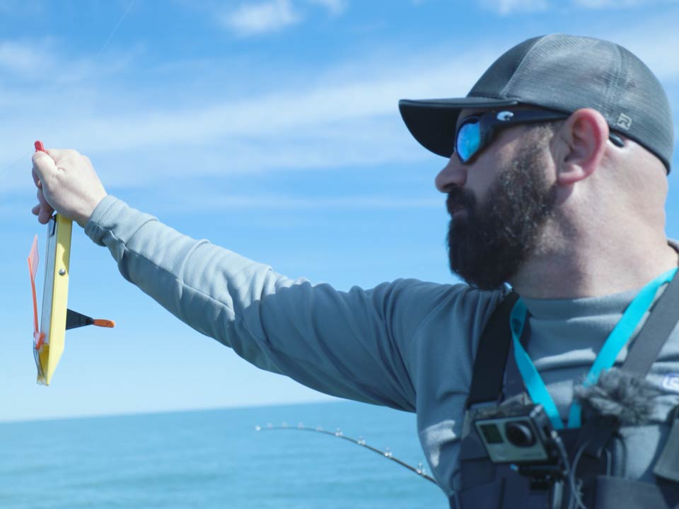 A close-up of a male angler holding a planer board to be used for trolling for Walleye on Lake Erie, Port Clinton, Ohio