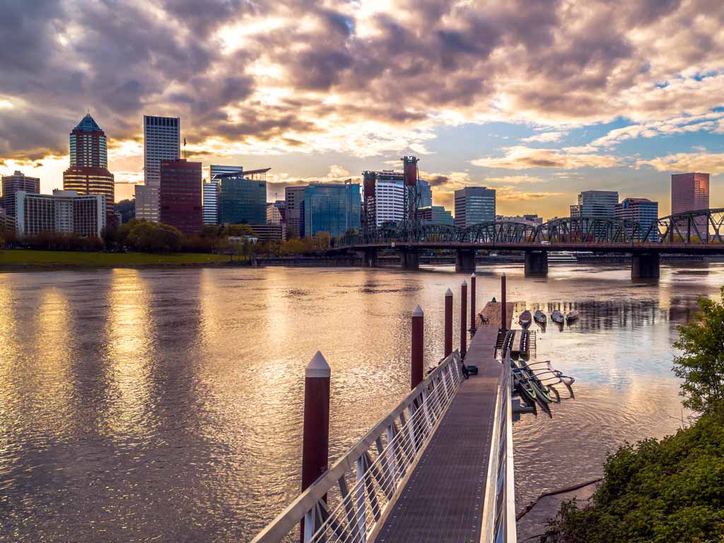 A sunset photo of the Portland skyline, taken from the shores of the Willamette River.