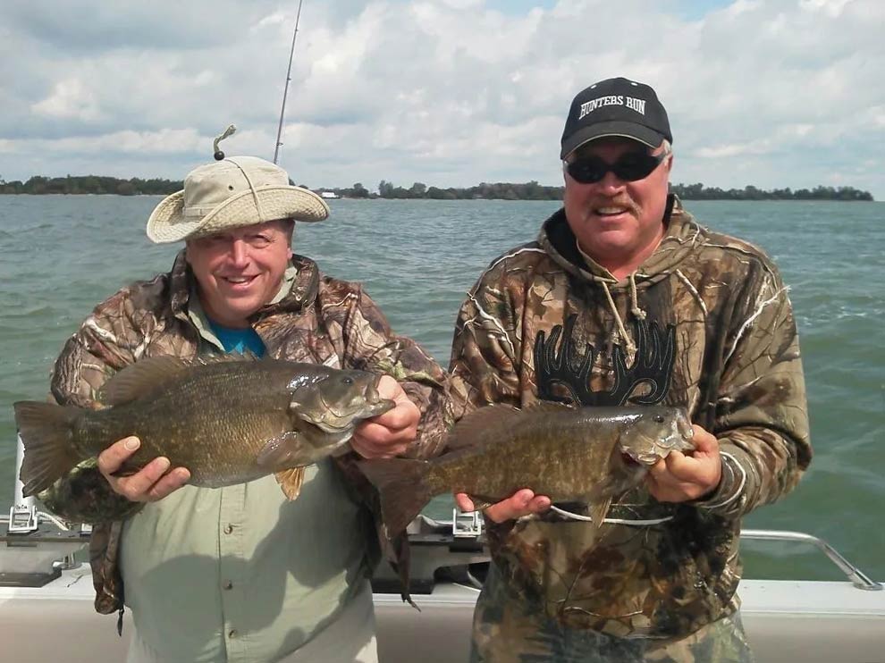 Two male anglers holding a Smallmouth Bass each caught on Lake Erie, Port Clinton, Ohio