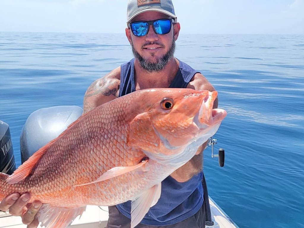 An excellent shot of an angler posing with his Snapper on a charter boat