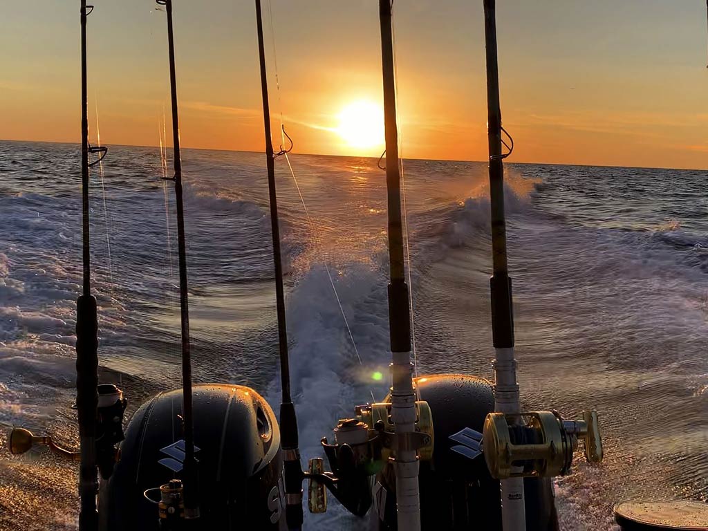 A sunset view of the motors, rods, and lines while trolling 