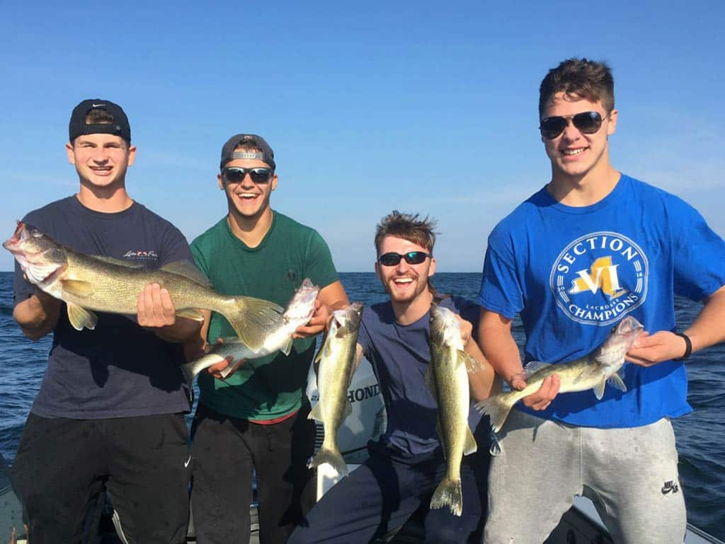 A group photo of four young anglers smiling and posing with their fish caught while fishing in Lake Eerie