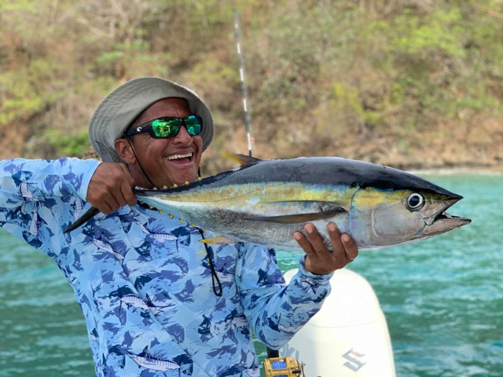 An excellent shot of a happy angler smiling and showing off his Yellowfin Tuna caught while fishing in Costa Rica