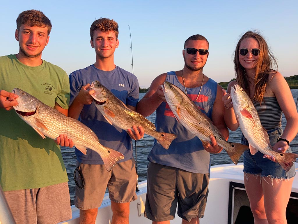 Four anglers holding the Redfish they recently caught on a fishing trip out of Corolla, NC.