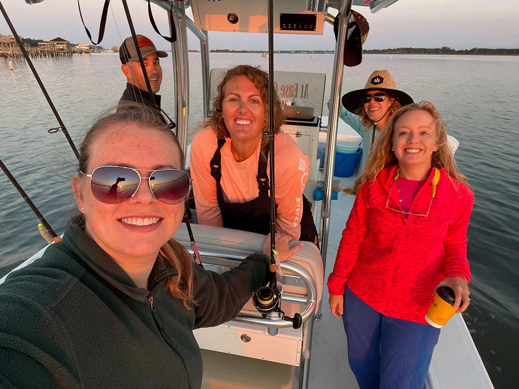 Four smiling anglers and a charter captain on the water outside Emerald Isle.