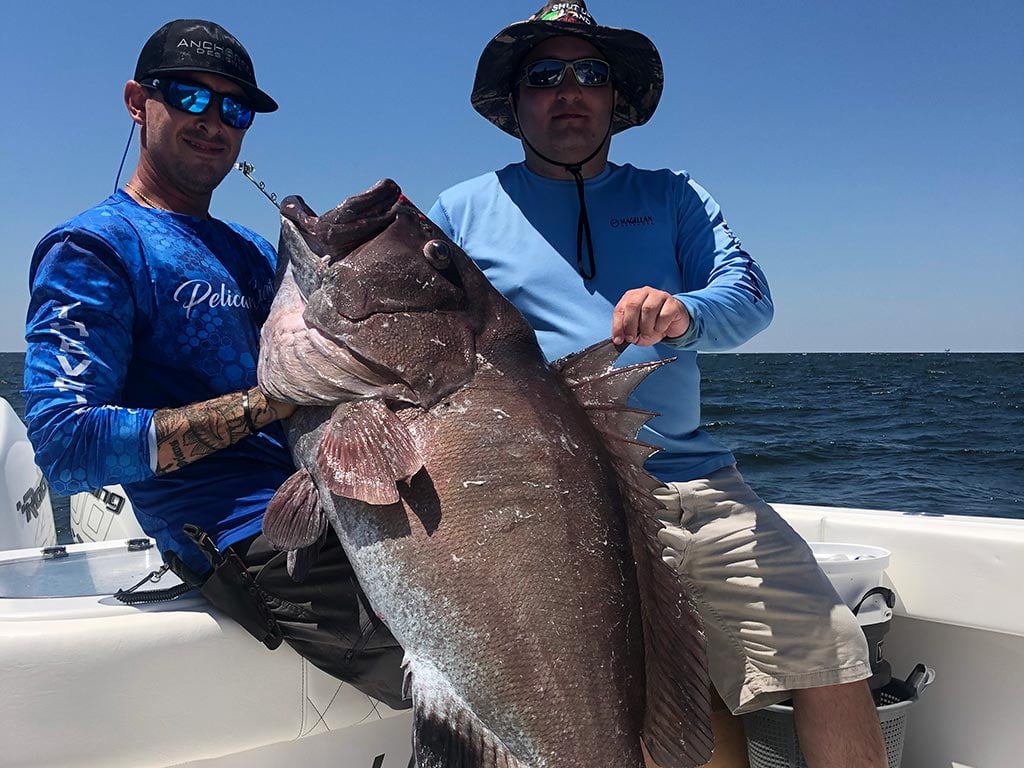 Two anglers hold a big Grouper they caught on a deep sea fishing trip.