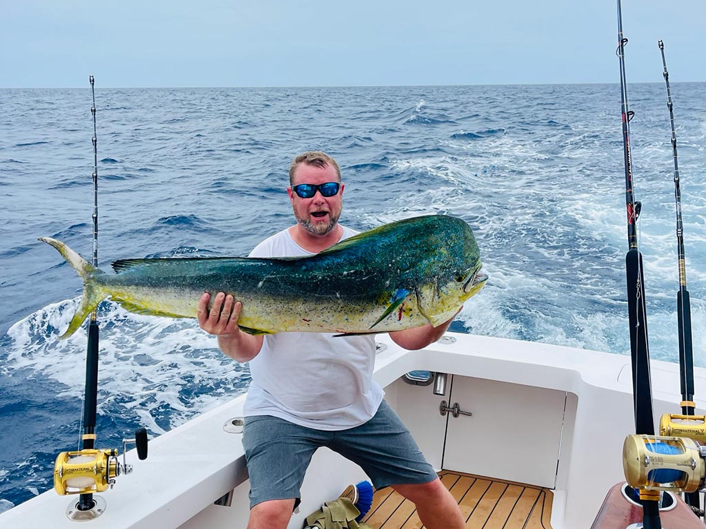 An excited angler holds a big Mahi Mahi caught on a trolling trip.