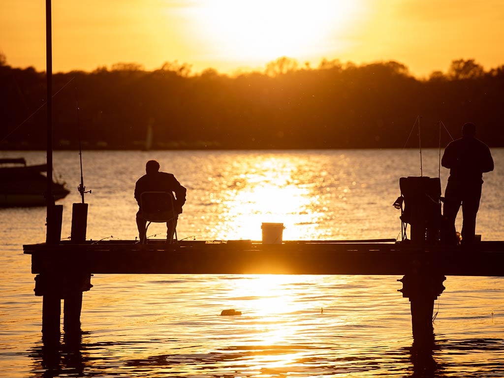 A rear-view image of two anglers on a pier at sunset, somewhere in Texas