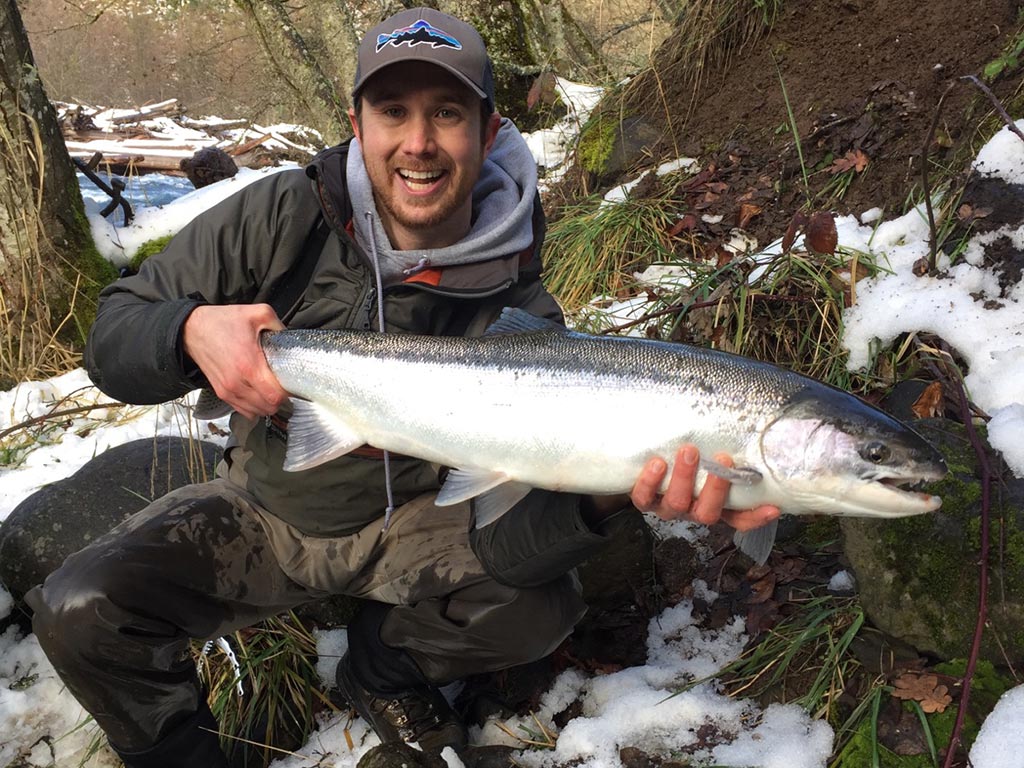 A smiling angler holds up a Salmon he caught somewhere on the Columbia River.