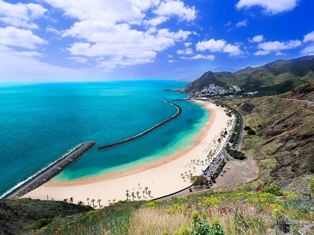 A view from the hill of a bay and beach in Tenerife, with a jetty protecting some of the nearshore waters