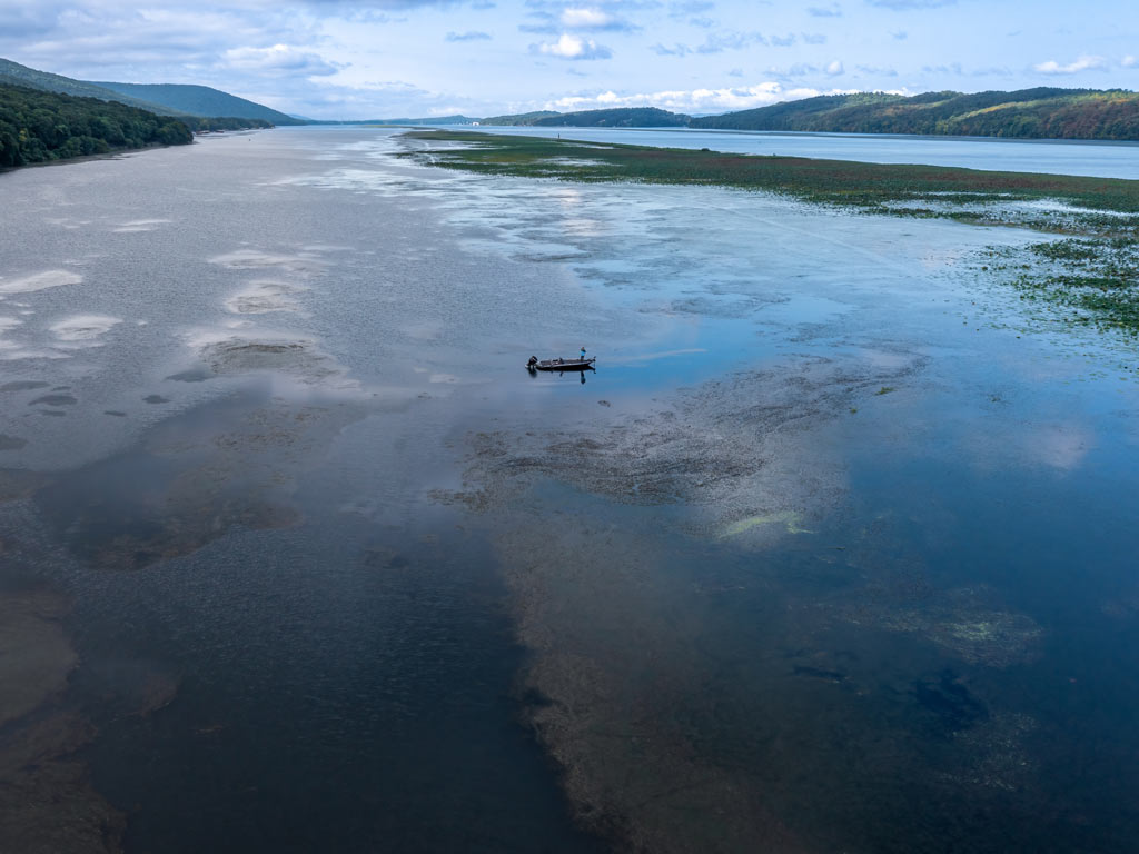 An aerial photo of Guntersville Lake, one of the best destinations to go fishing on Presidents' Day, with a Bass boat in the water.