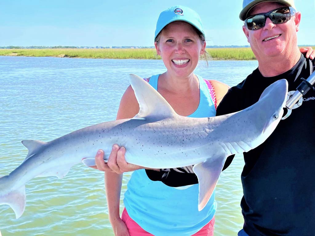 A photo of a woman and a man standing behind a Shark caught in South Carolina’s flats