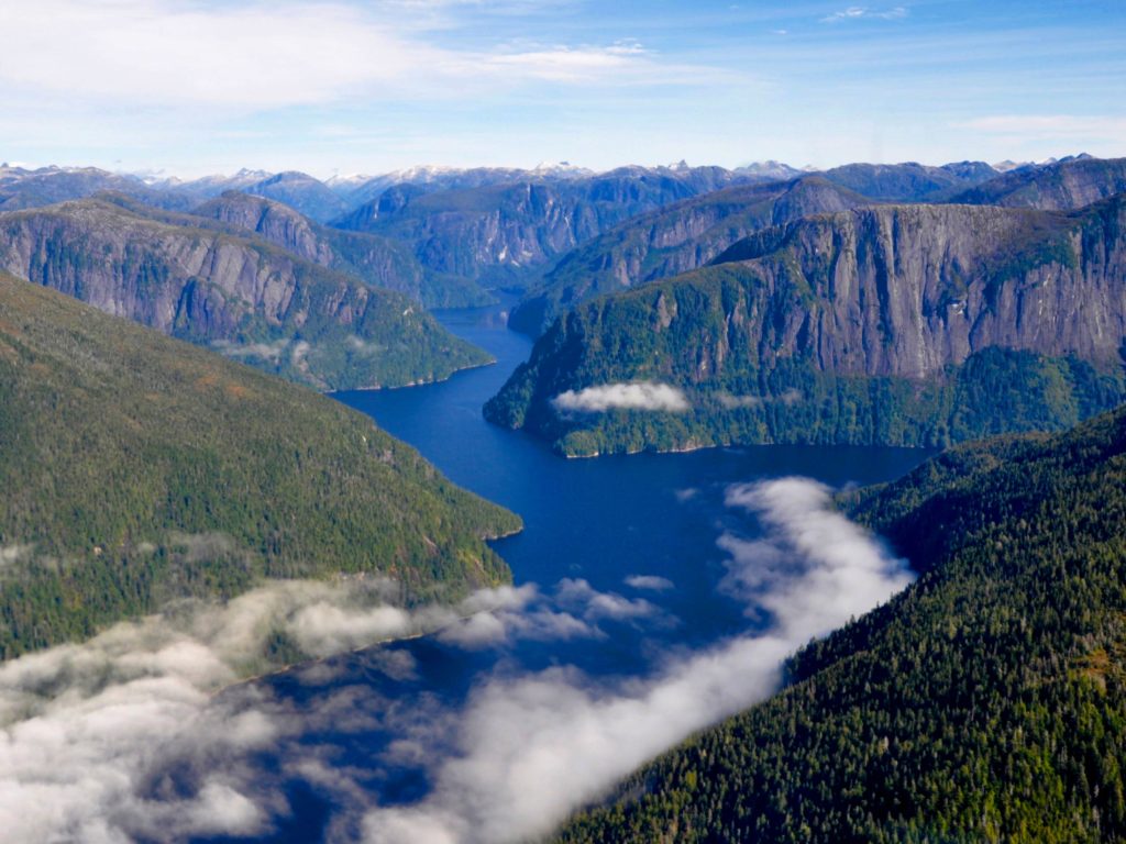 An aerial view of Misty Fjords National Monument in Tongass National Park with clouds rolling into the valley on a fall day in Alaska near Ketchikan