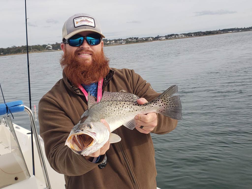 A happy angler holding his Trout catch on a cold and cloudy day