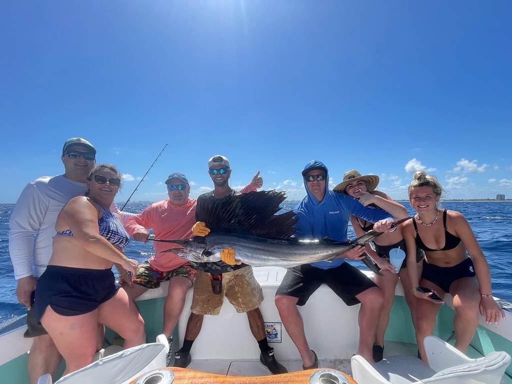 A group photo of several anglers happily posing on a charter fishing boat around A Sailfish caught in Florida during Spring Break