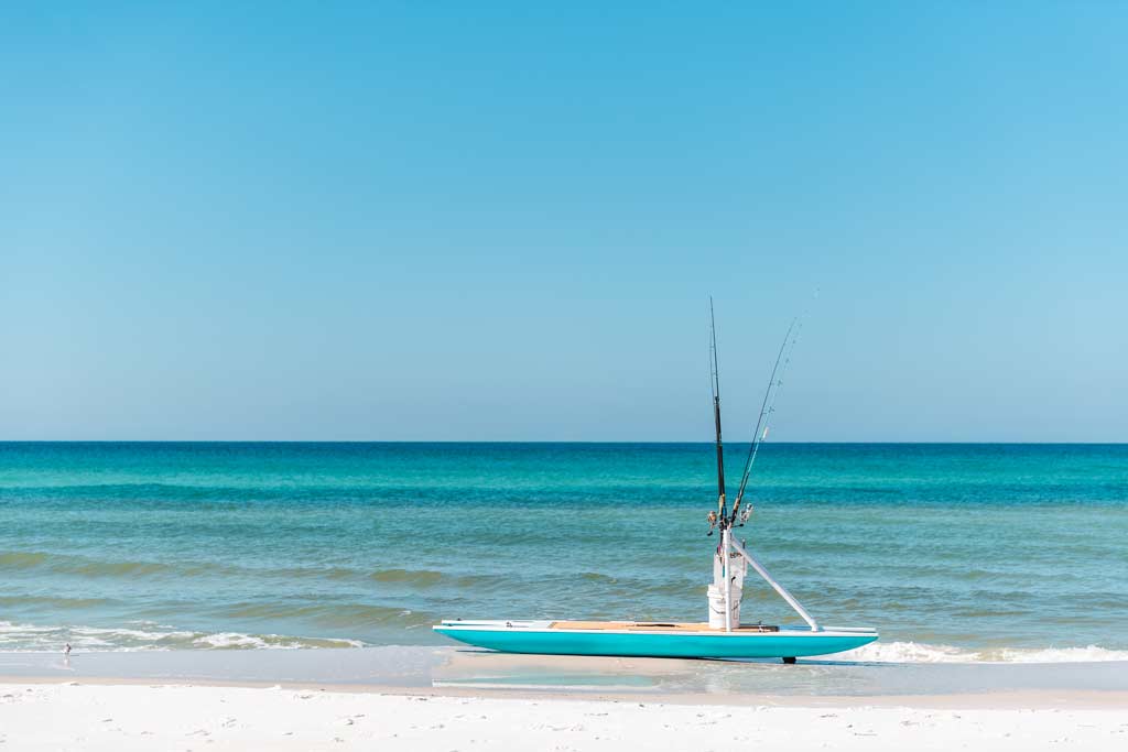 A lone fishing kayak without a fisherman moored in the shallow surf on the beach at St. George Island