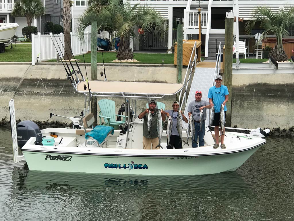 A photo of several angers standing on a charter boat docked in one of Cudjoe Key’s canals and posing with their fish caught earlier that day during a morning fishing trip