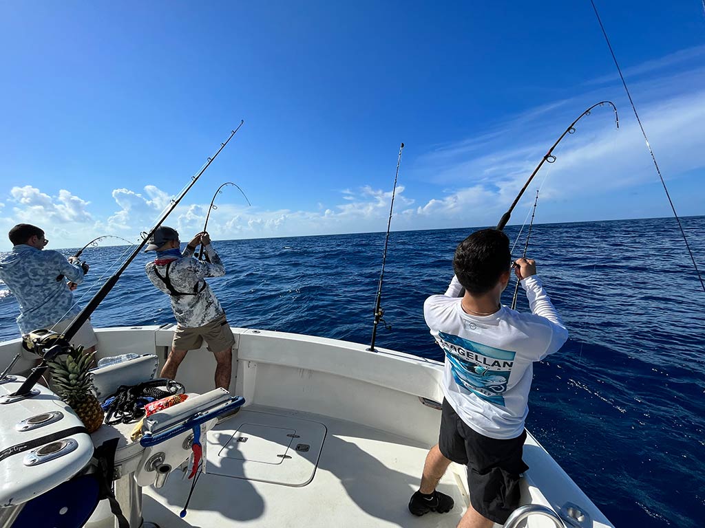 A rear-shot view of three anglers on the deck of a boat, marrow fishing with wilting rods in Texas on a well-spoken day