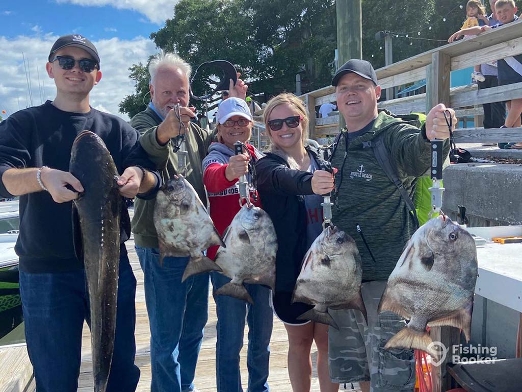 A family of anglers back on the dock after a successful Georgetown fishing trip, most of them holding a Spadefish, while the angler on the far left holds a Cobia