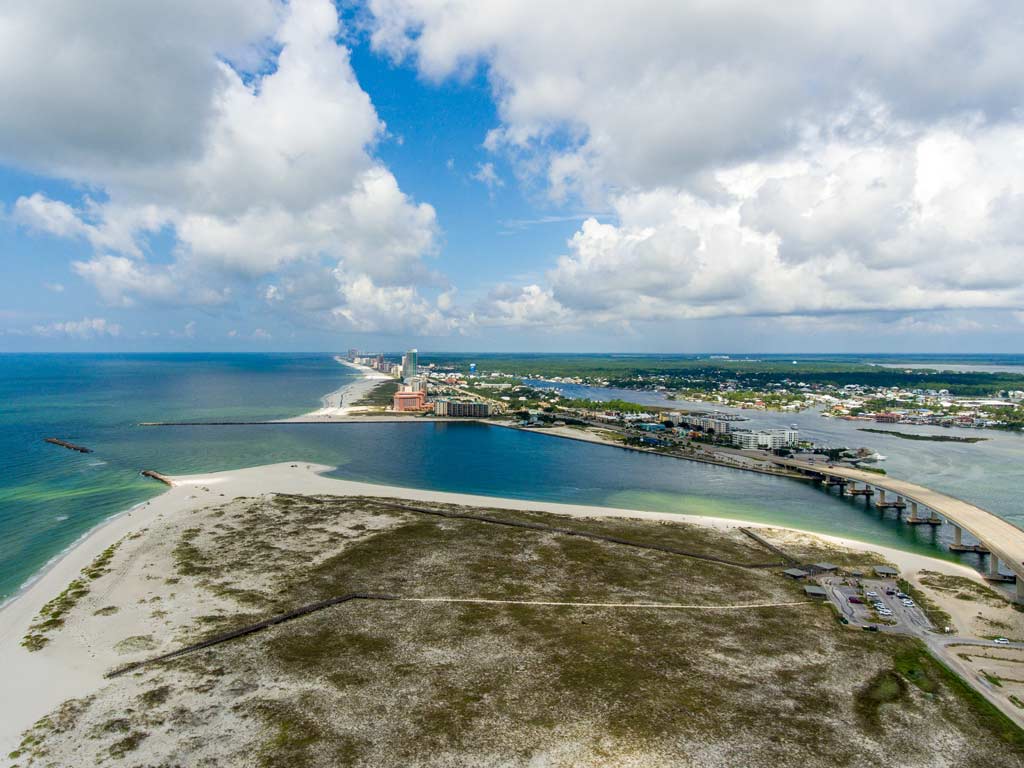 An aerial photo of Perdido Pass, with its two jetties visible on the left side of the photo, while the bridge is visible to the right.