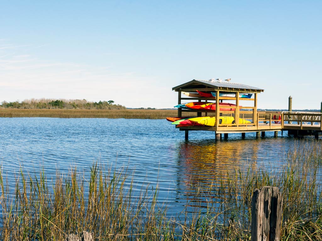 A photo featuring Georgia’s marshes and wetlands with a wooden structure fully loaded with kayaks for kayaking or kayak fishing