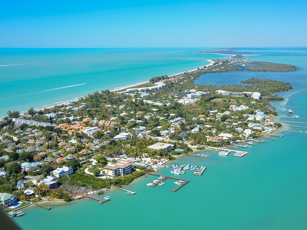 An aerial view of Captiva Island, taken on a sunny day, with the Gulf of Mexico in the distance on the left of the image and the bay on the right