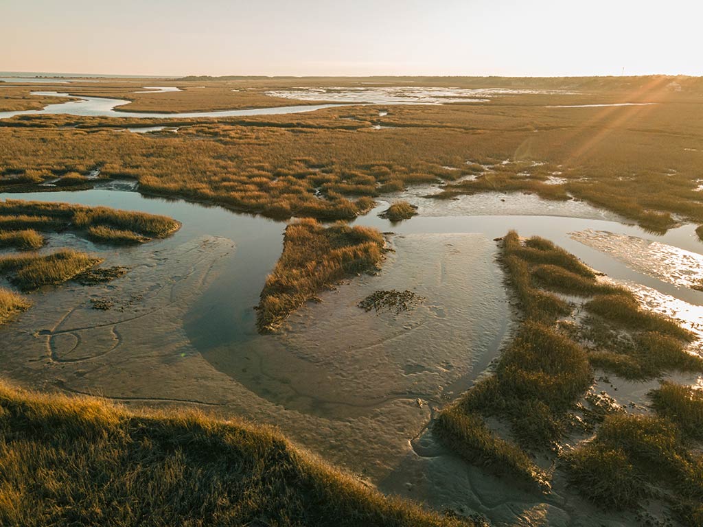 An aerial view of the winding waterways around the flats in Georgetown, SC, near sunset on a clear, sunny day