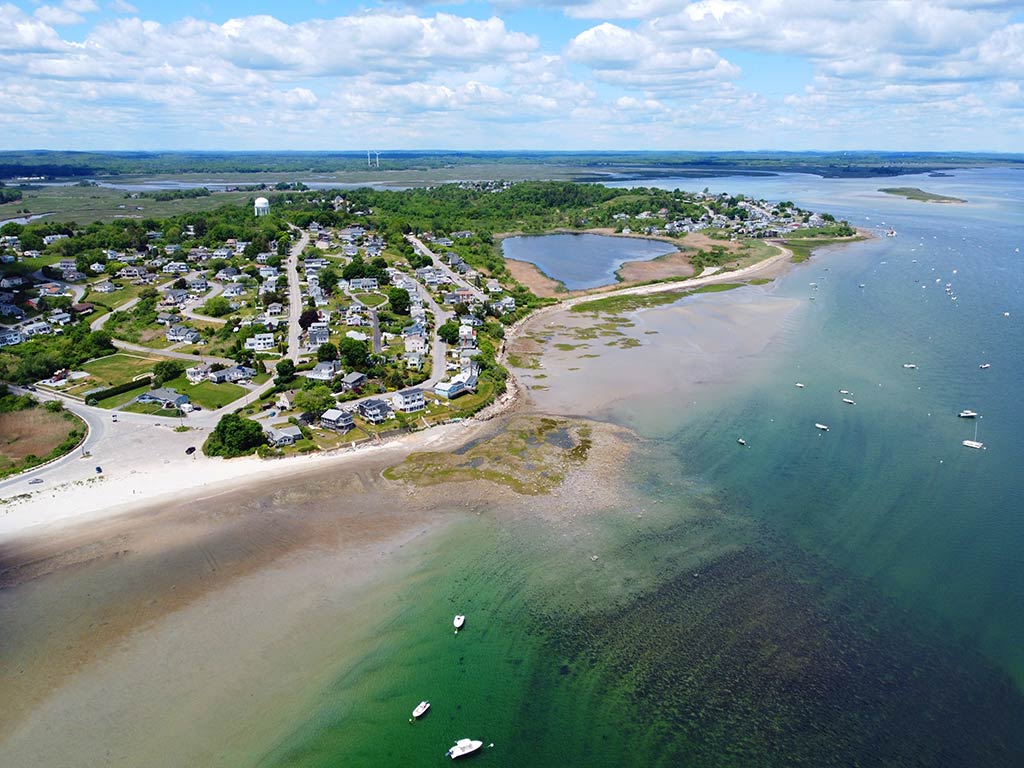 An aerial view of Ipswich Bay, showing the flats running from the beach to the ocean, beaches, and the town on the left-hand side of the image on a day with sunny intervals