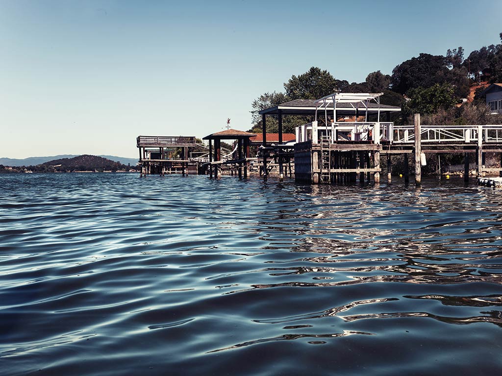 A view across the water towards a fishing station on Clear Lake, California, on a sunny day