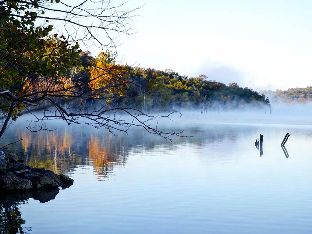 A view across the water on Table Rock Lake, as mist rises from it early in the morning on a crisp winter's day