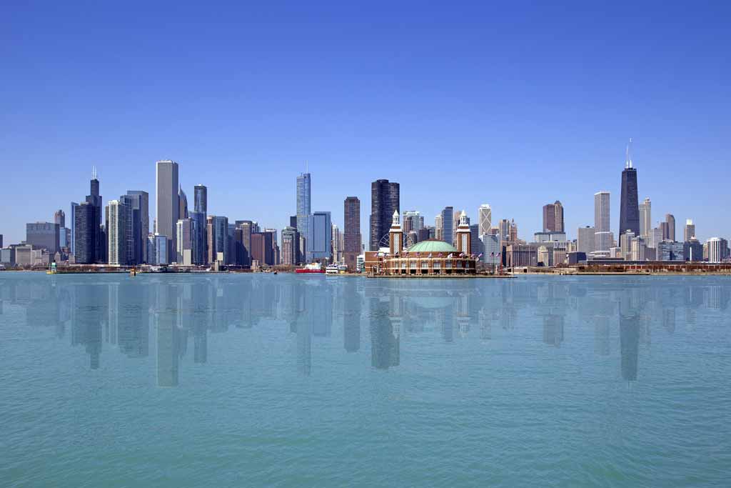 A view of the Chicago, Illinois skyline from the clear waters of Lake Michigan on a clear day, with a reflection of the high-rise on the lake