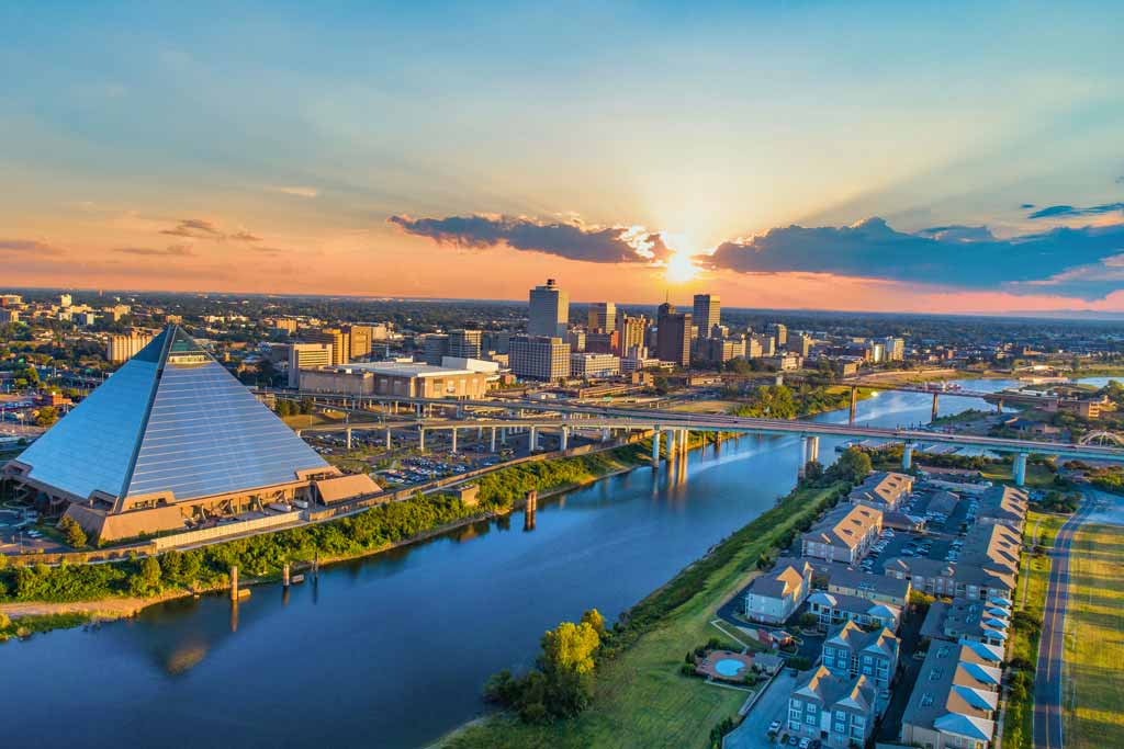 An aerial view of Memphis, Tennessee, with the Pyramid, Mississippi River, a bridge over it, and downtown photographed during sunset